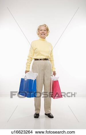 Picture - woman holding gift bags smiling . Fotosearch