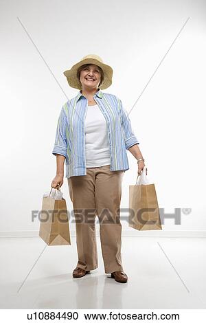 Stock Image - Woman holding gift bags smiling. Fotosearch