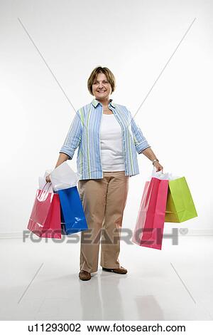 Stock Image - Woman holding gift bags smiling. Fotosearch