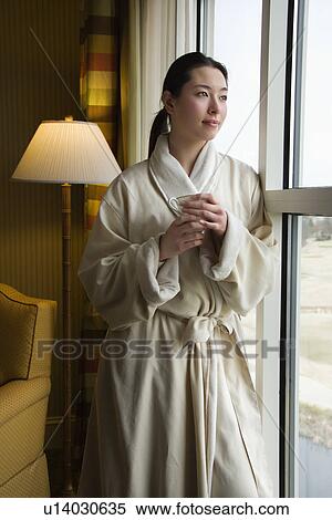 Woman in bathrobe looking out window holding cup. View Large Photo Image Stock Photography - Woman in bathrobe looking out window holding cup.. Fotosearch