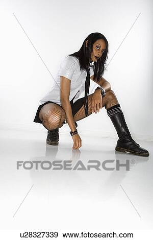 Stock Photo - Woman in mini skirt and boots kneeling. Fotosearch