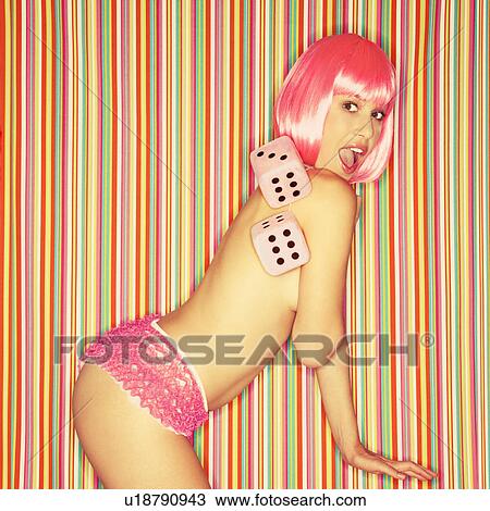 Stock Image - Woman in underwear wearing pink wig holding dice against striped background. Fotosearch