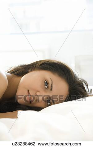 Stock Image - Woman laying on bed. Fotosearch