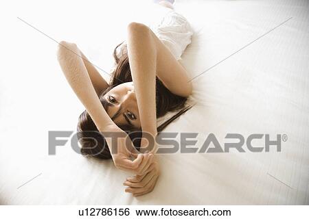Stock Photograph - Woman laying on bed wearing nightgown. Fotosearch