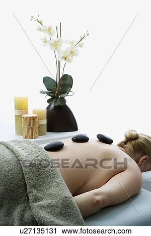 Woman lying on massage table with hot stones on her back View Large Photo Image Stock Image - Woman lying on massage table with hot stones on her back. Fotosearch