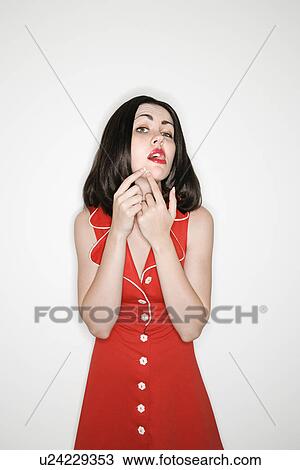 Stock Image - Woman making facial expression while popping a zit . Fotosearch