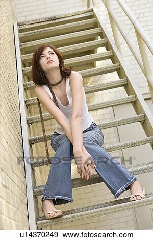 Stock Photo - Woman sitting on fire escape.. Fotosearch