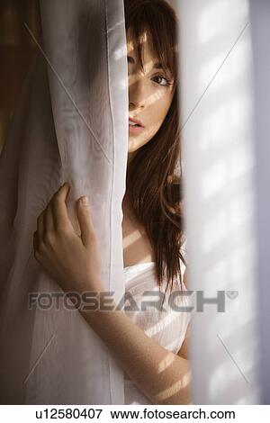 Woman standing in sunlit curtains View Large Photo Image Stock Photo - Woman standing in sunlit curtains. Fotosearch