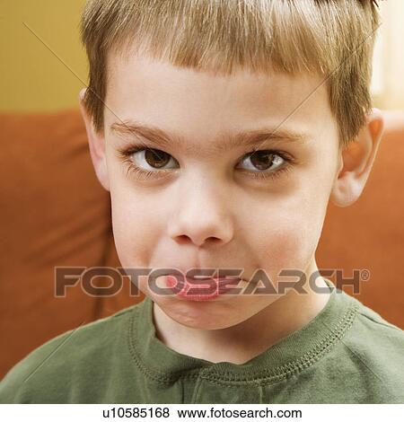 Stock Photo - Young boy pouting and looking at viewer.. Fotosearch