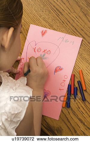 Stock Image - Young child drawing on paper with crayons. Fotosearch