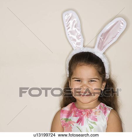 Picture - Young girl wearing bunny ears smiling and looking at viewer.. Fotosearch