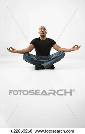 Stock Photo - Young male adult sitting and meditating. Fotosearch