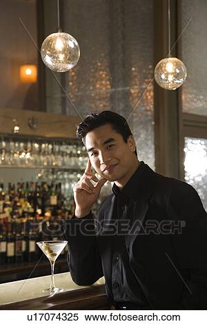 Young man standing at bar with cocktail. View Large Photo Image Stock Photography - Young man standing at bar with cocktail.. Fotosearch