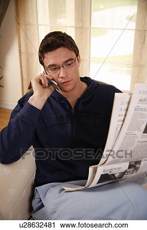 Man reading newspaper and talking on cell phone View Large Photo Image Stock Image - Man reading newspaper and talking on cell phone. Fotosearch