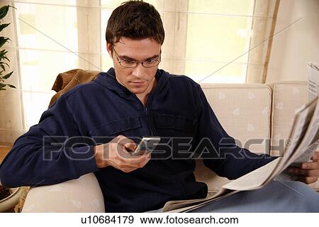 Man reading newspaper and talking on cell phone View Large Photo Image Stock Photo - Man reading newspaper and talking on cell phone. Fotosearch