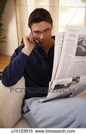 Stock Photography - Man reading newspaper and talking on cell phone. Fotosearch