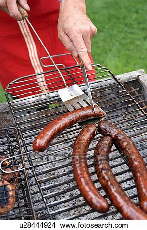 Picture - Mature man cooking food at a barbecue. Fotosearch