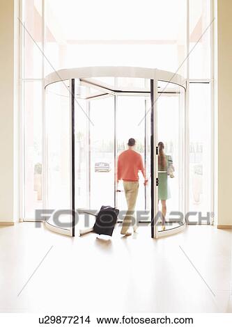 Picture - Couple leaving hotel with luggage, rear view. Fotosearch