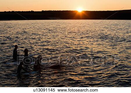 Four people sitting on surfboards in the water. View Large Photo Image Stock Photography - Four people sitting on surfboards in the water.. Fotosearch