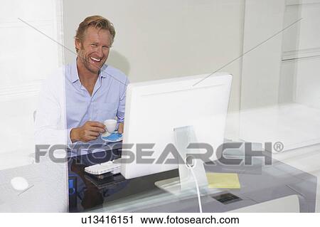 Stock Image - Man at computer smiling with reflections.. Fotosearch