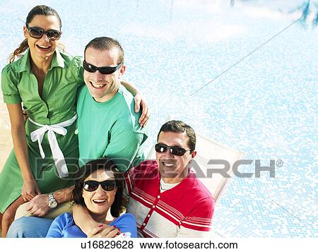 Two couples sitting by swimming pool, smiling View Large Photo Image Stock Photo - Two couples sitting by swimming pool, smiling. Fotosearch