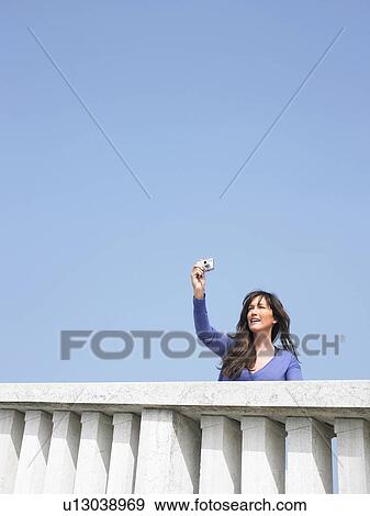 Woman on balcony taking photograph with digital camera. Venice, Italy. View Large Photo Image Stock Photo - Woman on balcony taking photograph with digital camera. Venice, Italy.. Fotosearch