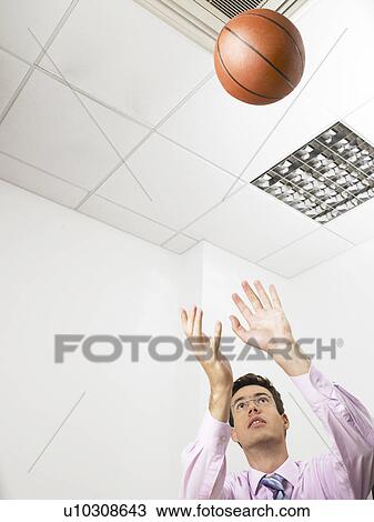 Businessman in an office throwing a basketball View Large Photo Image Stock Image - Businessman in an office throwing a basketball. Fotosearch