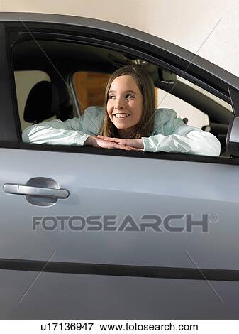 Stock Photo - Girl (12-14) sitting in car, leaning out of window, smiling. Fotosearch