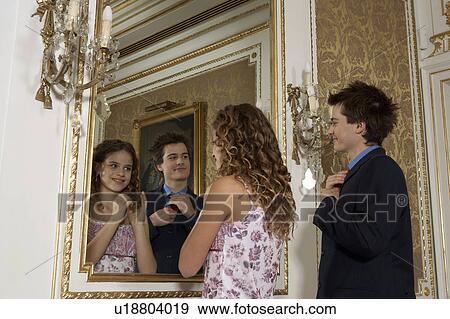 Stock Photo - Girl (9-11) and teenage boy (15-17) looking in mirror. Fotosearch