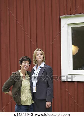 Stock Image - Mother and daughter outside country cottage. Fotosearch
