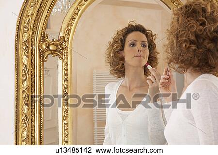Stock Image - woman applying lipstick in mirror. Fotosearch