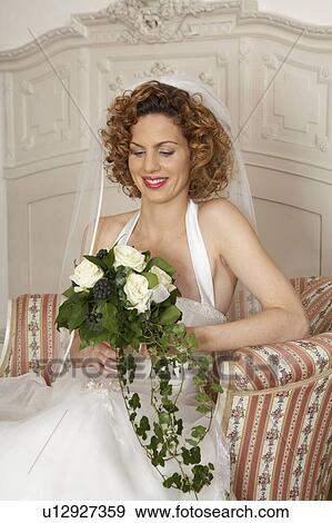young bride smiling sitting looking down holding bridal bouquet View Large Photo Image Stock Photo - young bride smiling sitting looking down holding bridal bouquet. Fotosearch