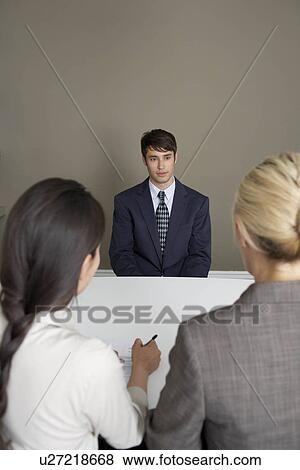 Stock Photo - 2 businesswomen interviewing man. Fotosearch
