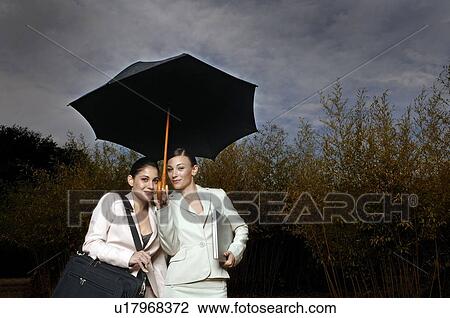 2 women under an umbrella View Large Photo Image Stock Image - 2 women under an umbrella. Fotosearch