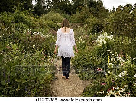 A female walking through a garden View Large Photo Image Stock Photo - A female walking through a garden. Fotosearch