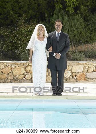 Bride and groom by edge of swimming pool View Large Photo Image Stock Photo - Bride and groom by edge of swimming pool. Fotosearch