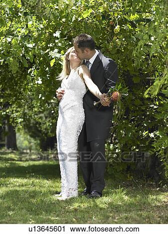 Bride and groom kissing in garden View Large Photo Image Stock Image - Bride and groom kissing in garden. Fotosearch