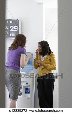 Stock Image - Businesswomen gossiping in office. Fotosearch