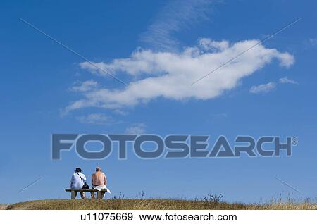 Stock Photo - Couple sitting, looking to the distance. Fotosearch