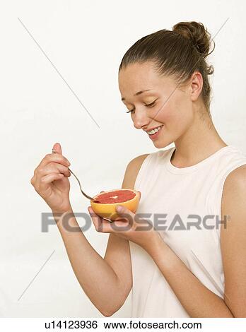 Girl eating a pink grapefruit View Large Photo Image Stock Photograph - Girl eating a pink grapefruit. Fotosearch