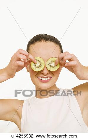 Girl holding kiwi slices over her eyes View Large Photo Image Stock Image - Girl holding kiwi slices over her eyes. Fotosearch