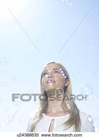 Stock Photography - Girl looking at sky with bubbles. Fotosearch