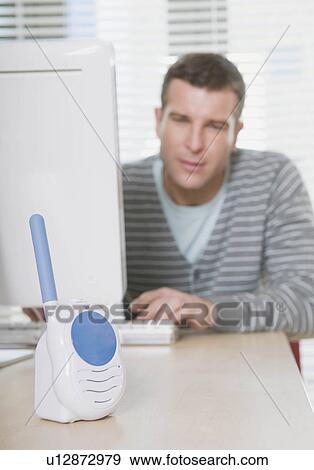 Man listening to baby monitor at work View Large Photo Image Stock Photo - Man listening to baby monitor at work. Fotosearch