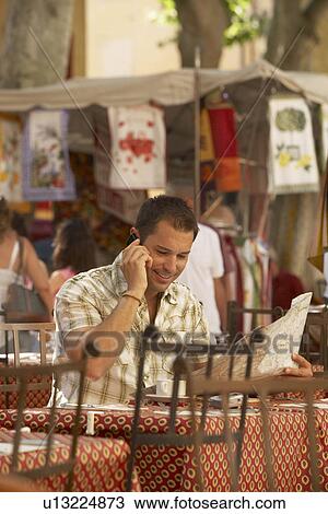 Stock Image - Man talking on phone in french cafe. Fotosearch