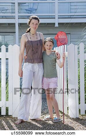 Stock Photo - Sisters pose outside a beach house. Fotosearch