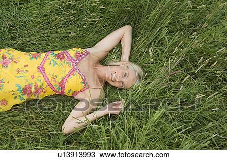 Stock Image - Smiling woman lying in field. Fotosearch