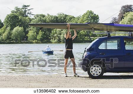 Stock Image - Woman lifting canoe off car. Fotosearch