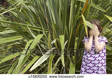 Stock Image - Young girl hiding her face. Fotosearch