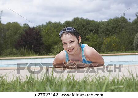 Stock Image - Young girl smiling by swimming pool. Fotosearch