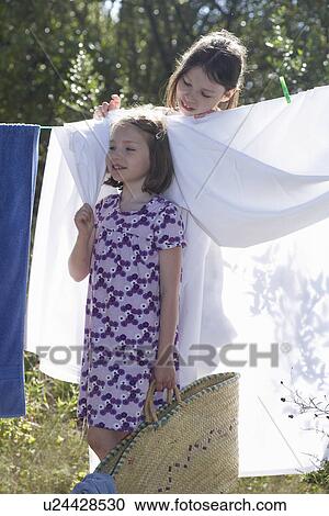 Stock Image - Young girls standing by washing line. Fotosearch